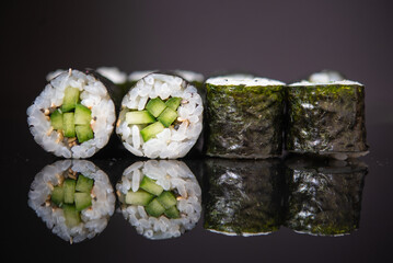 Assorted sushi rolls with salmon tuna cucumber and sesame seeds on dark background © Lemonade