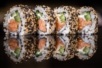 Assorted sushi rolls with salmon tuna cucumber and sesame seeds on dark background © Lemonade