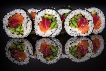 Assorted sushi rolls with salmon tuna cucumber and sesame seeds on dark background © Lemonade