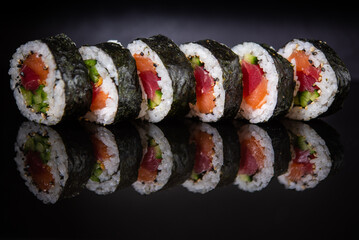 Assorted sushi rolls with salmon tuna cucumber and sesame seeds on dark background © Lemonade