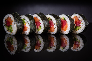 Assorted sushi rolls with salmon tuna cucumber and sesame seeds on dark background © Lemonade