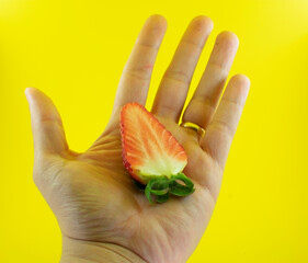 mão com lindo morango vermelho e fundo amarelo