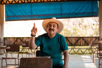 Fototapeta na wymiar An older adult raises his hand to give his opinion in a classroom in the middle of the jungle