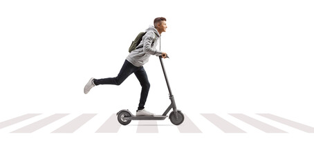 Full length shot of a male student with a backpack riding an electric scooter at pedestrian zebra crossing © Ljupco Smokovski