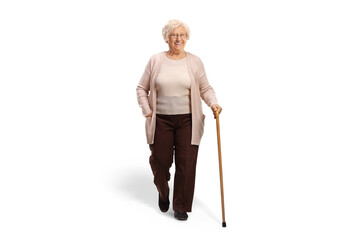 Full length portrait of a senior woman with a cane walking towards camera - obrazy, fototapety, plakaty