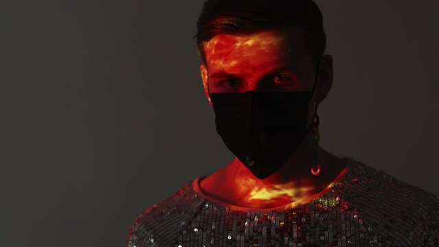Stylish look. Lgbtq male portrait. Safety desiase. Gay man in spangle shirt black protective mask posing gray background with double exposure sunset light overlay reflection lens flare.