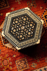 hexagonal middle eastern, moroccan inlaid box design on patterned rug