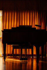 silhouette of baby grand piano with golden curtains