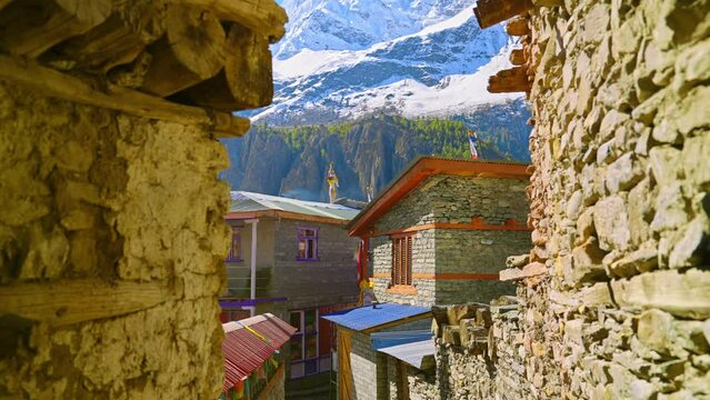 Traditional stone buildings in the village of Manang, Nepal with views of the mountainous landscape of the Himalayas on a sunny day, Annapurna Circuit
