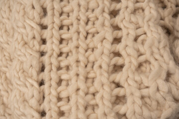 A fragment of beige knitted fabric, knitted from white sheep wool.