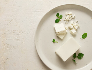 cheese briquette for salads, Danish, white, top view, on a white plate,