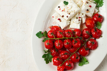 baked cherry tomatoes , with cheese, and spices, on a white plate, homemade, no people,