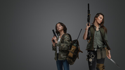 Studio shot of two female survivors with guns in post apocalyptic style.