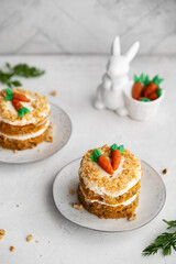 Easter Carrot cake with cream cheese frosting and marzipan decorations on a white stone background for festive dinner. Small easter bento cake. Fresh homemade carrot cake. Traditional Easter food.