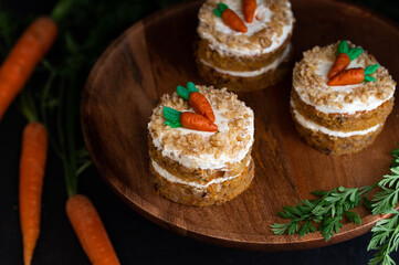 Easter Carrot cake Rüeblitorte with cream cheese frosting and marzipan decorations on a wood plate for festive dinner. Small easter bento cake. Fresh homemade carrot cake. Traditional Easter food. 