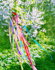 Spring floral wreath with colorful ribbons on tree in garden, green natural background. floral...