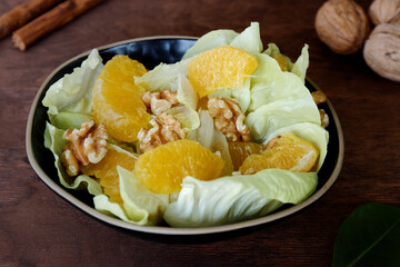 Orange salad with orange fruit, romaine lettuce and walnut nuts. Fresh, homemade salad.