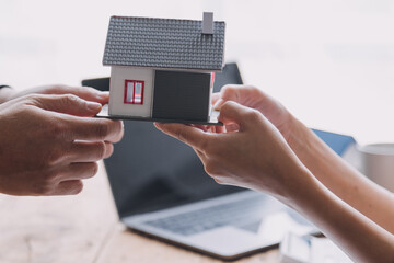 Real estate broker agent presenting and consult to customer to decision making sign insurance form agreement, buy and sell home model, concerning mortgage loan offer for and house insurance