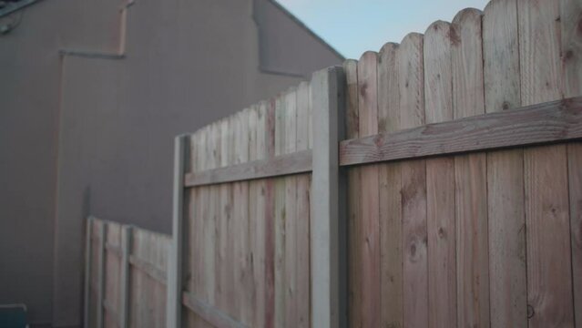 Garden fence walking along wooden dividing fence between houses slow motion tracking shot