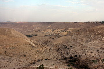 Desert landscape view of sunny rocky cliff with wind turbines in view taken from Shobak Castle, Jordan