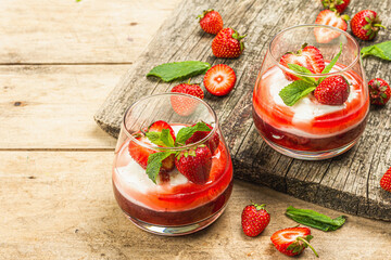 Italian dessert panna cotta in glass with strawberries. Healthy sweet food, hard light, dark shadow
