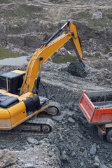 modern excavator loading soil into truck at construction site - 584420856