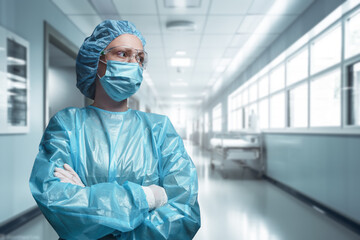 Shot of surgeon woman posing with crossed arms against corridor of modern hospital.