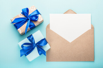 Two gift box with a blue ribbon and a bow and a greeting blank with envelopes on a blue background.Greeting card.