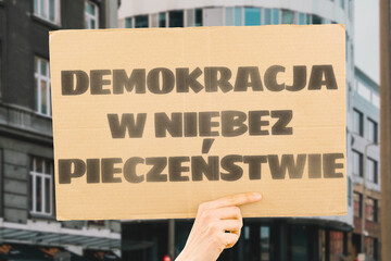 The phrase " Democracy in danger " is on a banner in men's hands with blurred background. Politics. Problem. Solution. Protest. Political crisis. Collapse. Crush