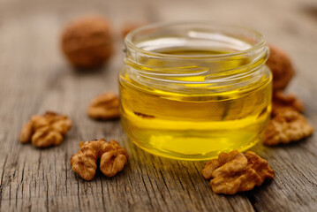 Walnut oil in glass jar, whole big peeled walnut kernel.