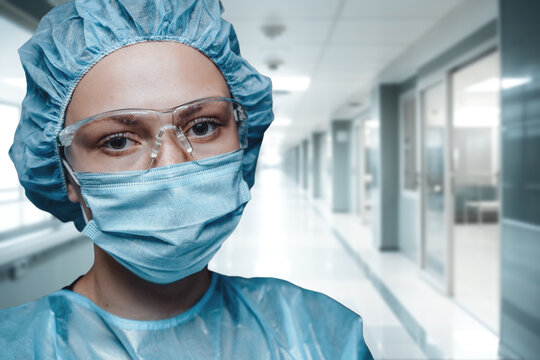 Shot of surgeon woman with rubber uniform and glasses looking at camera.
