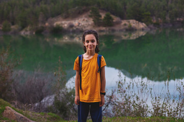 happy child stands on the background of a mountain lake..Child with a backpack. Vacation with children