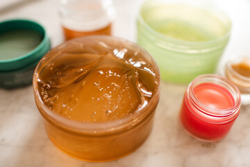 Aloe or snail mucin gel in plastic jar with skin care products on table in bathroom close up....