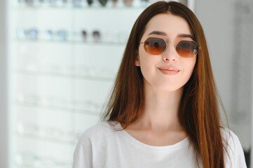 She made her choice. Beautiful young woman adjusting her new sunglasses and smiling while standing in optic store.