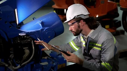 Caucasian male engineer, technician wearing safety uniform working using tablet Online information to monitor machine operation, check  maintenance plan to make a machine work efficiently and safety.