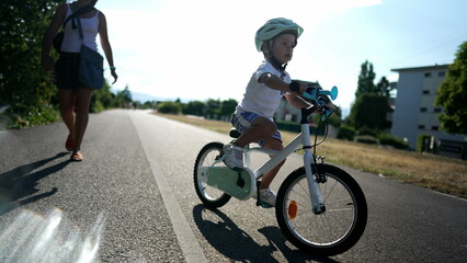 Obraz premium One active little boy riding bicycle outdoors in urban bike road. Little kid wearing a protective helmet staying in balance. Handheld slow motion footage