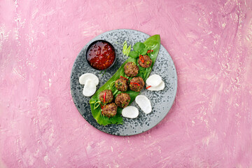 Traditional Asian street food meatballs served with krupuk prawn cracker and spicy chili sweet sour sauce on a Nordic design plate as top view with text space