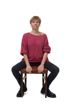 front view of a woman in tight jean pants sitting on chair looking at camera and open legs on white background