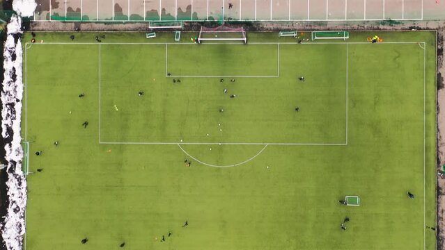 Drone footage of football game practice in soccer field during winter cloudy day