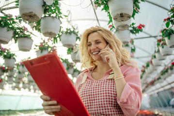 Young woman working in a greenhouse and using a smartphone