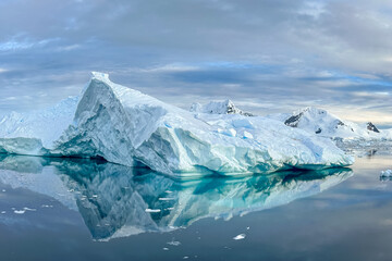 Fototapeta na wymiar Impressive iceberg with blue ice and beautiful reflection on water in Antarctica, scenic landscape in Antarctic Peninsula