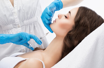 Beautician makes anti-aging injections against fat deposits on the chin of a beautiful woman....