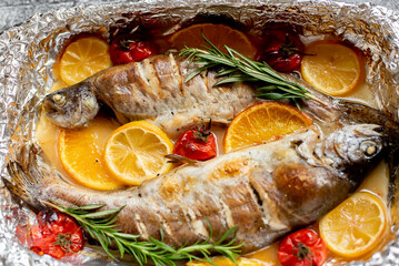 baked trout with lemon, orange, spices on a stone background