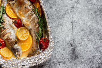 baked trout with lemon, orange, spices on a stone background with copy space for your text