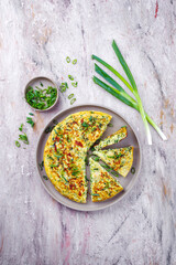 Traditional Italian vegetable frittata with zucchini, spring onion and cheese served as top view on Nordic design plate with text space