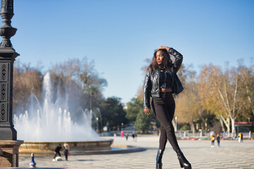 Young, beautiful, Latin and South American woman with leather jacket and top, jeans and platform shoes, touching her hair posing sensual and beautiful. Concept beauty, fashion, diversity, latina.