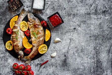 baked trout with lemon, orange, spices on a stone background with copy space for your text