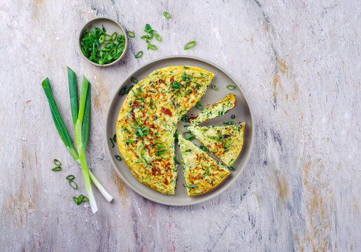 Traditional Italian vegetable frittata with zucchini, spring onion and cheese served as top view on Nordic design plate with text space
