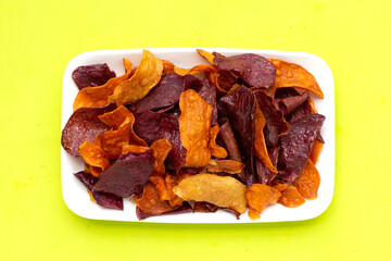 Purple and yellow sweet potato chips on green background