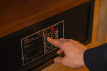A hand enters a code to open and lock a safe or safe in a hotel room Theft or keeping valuables